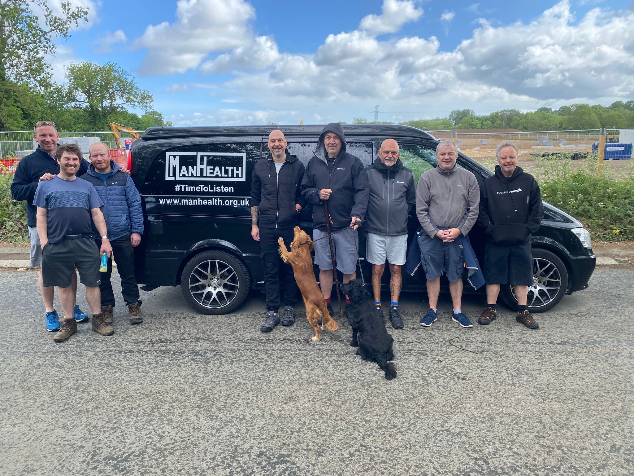 group of men standing in front of a black van